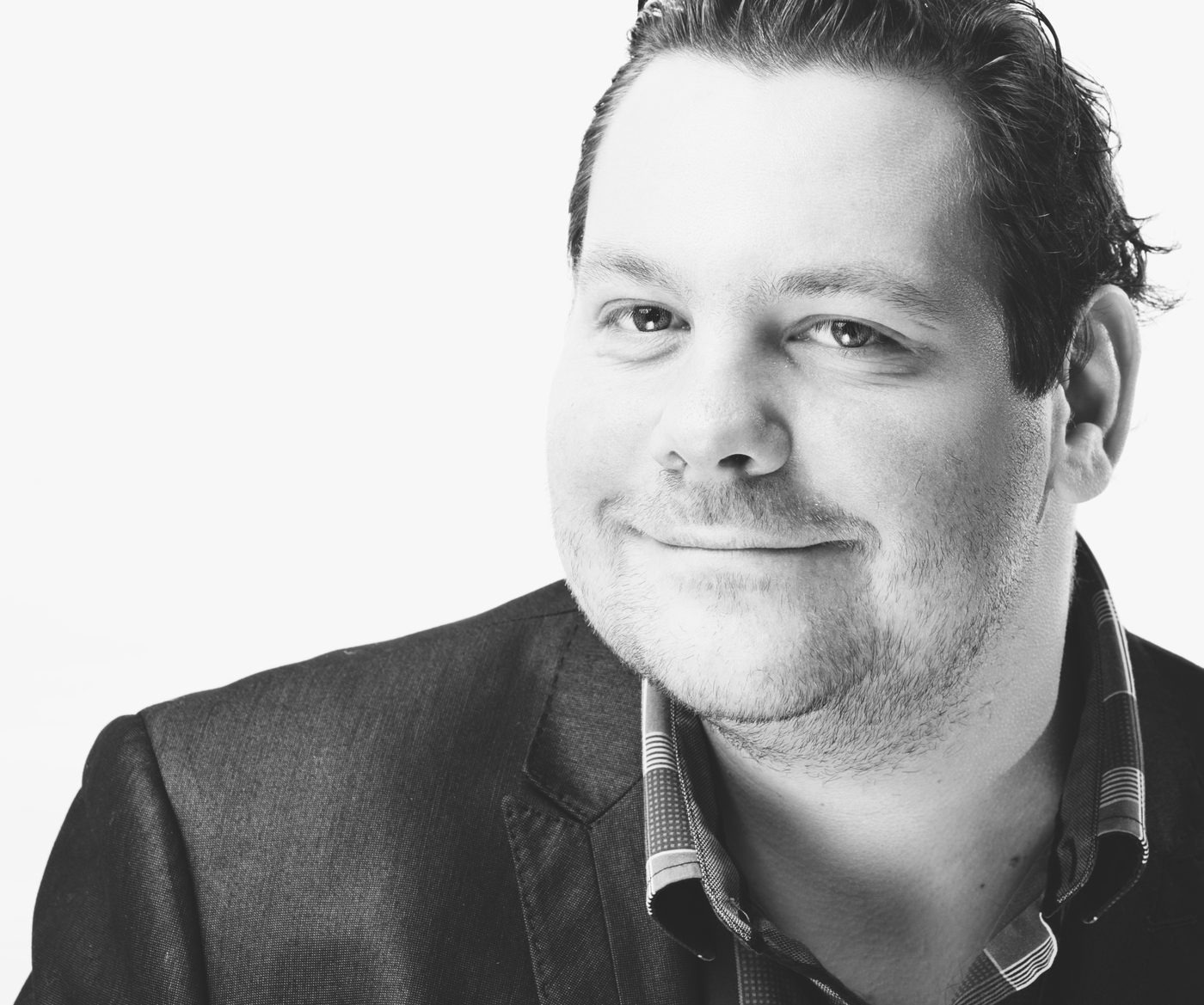 Portrait en noir et blanc de Marc-André Laurier Thibault, souriant, en veston.